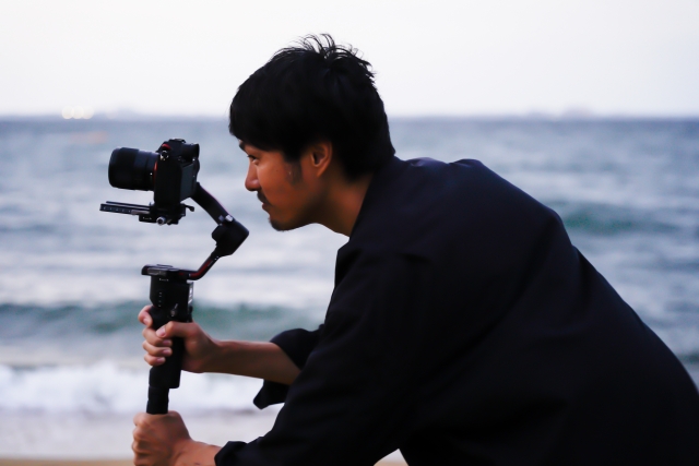 海を背景に撮影するカメラマン